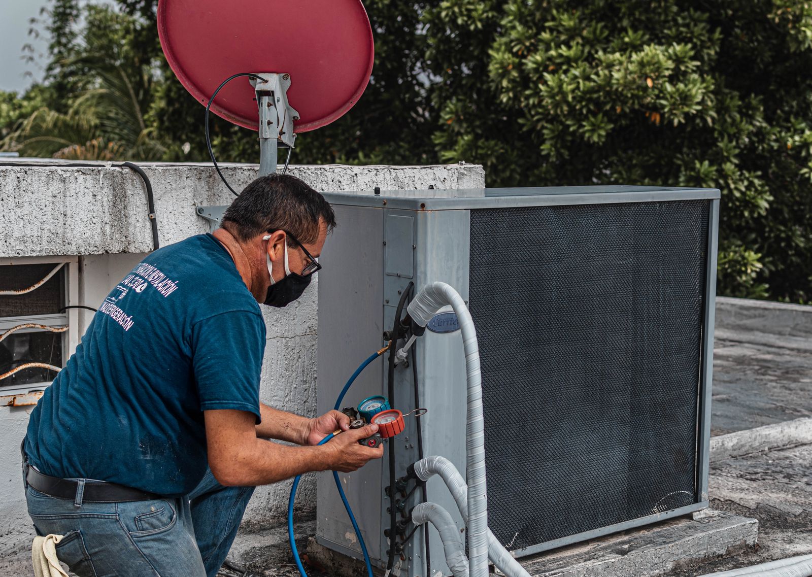 Technician repairing an outdoor air conditioner unit with a manifold gauge