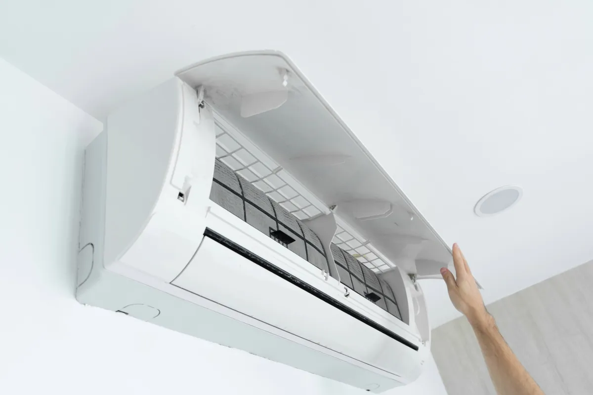 Hand opening the cover of a wall-mounted ductless air conditioner
